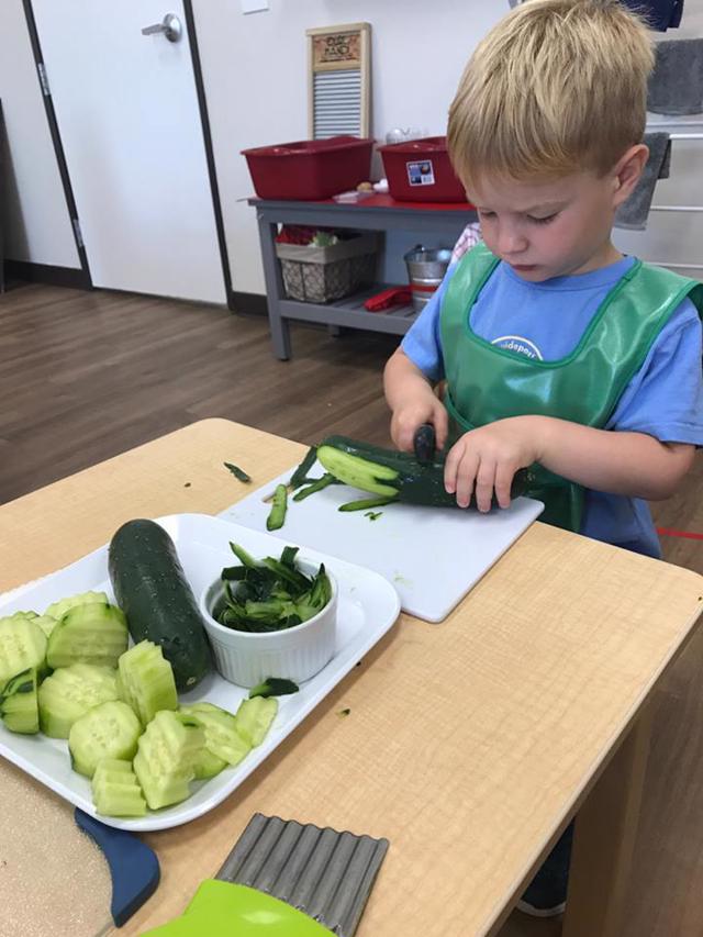 Best Private Montessori School Frisco, TX Student works independently cutting vegetables at Guidepost Montessori at Stonebriar