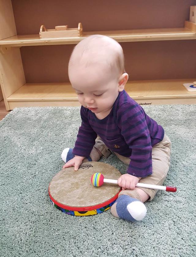 Nido student playing drum builds gross motor skills at Guidepost Montessori in Frisco, TX | Private School