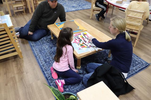 Elementary student shows her parents the United States puzzle map with the names of the states. As she continues on this geography lesson, she will identify the state capitals at Guidepost Montessori in Frisco, TX | Best private school